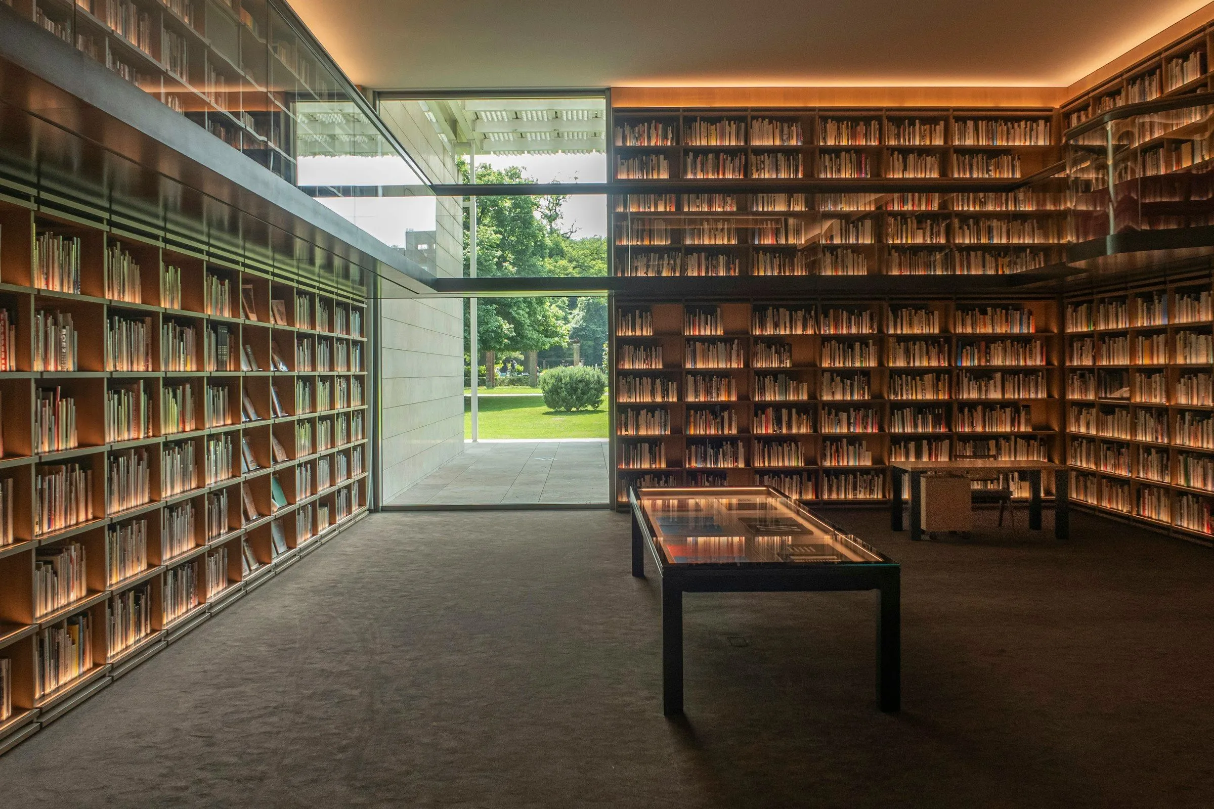 Werkkamer met boekenwanden aan weerszijden en een glazen pui naar de tuin
