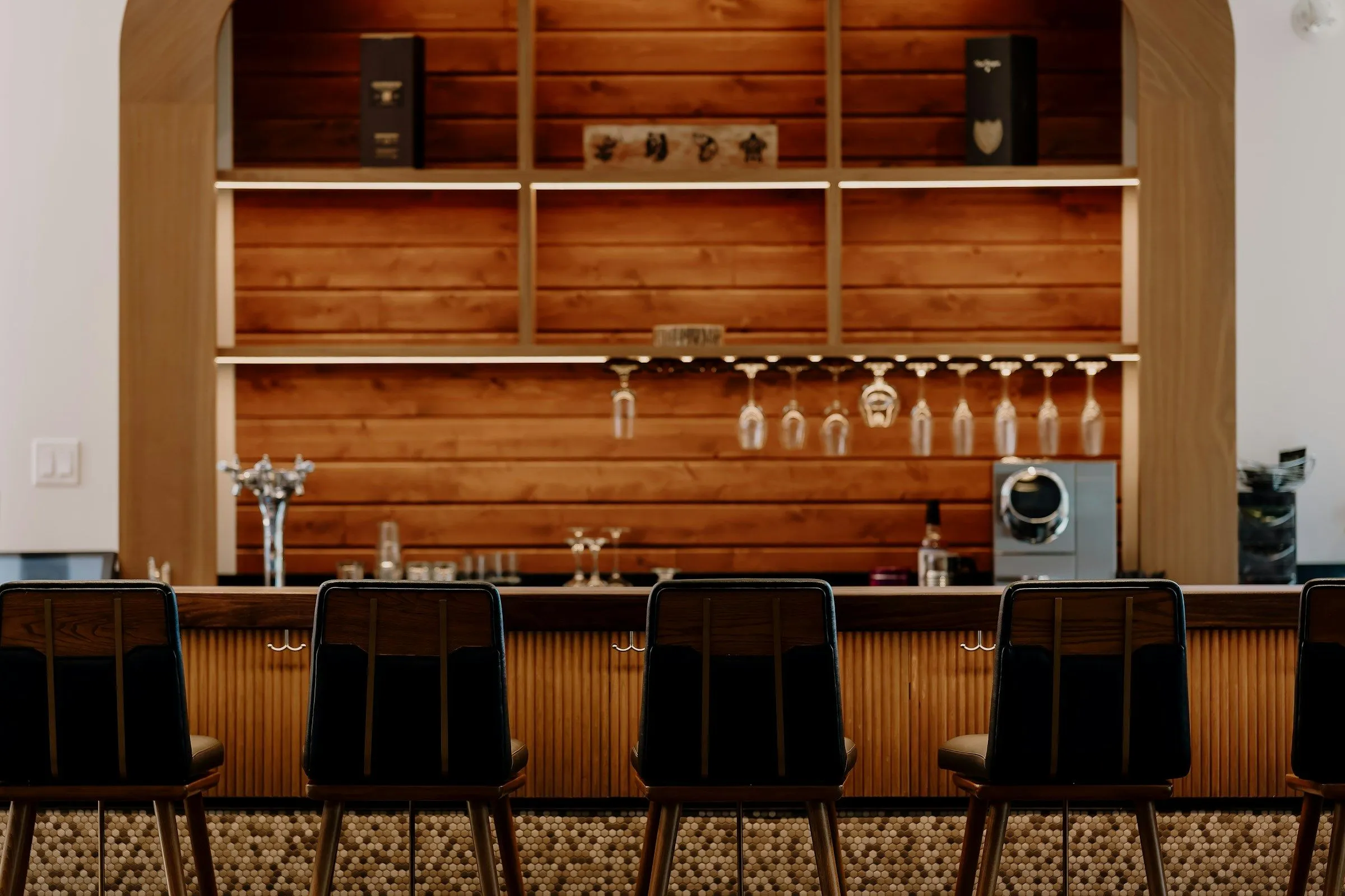 Houten bar met zwarte krukken voor een wand van open planken
